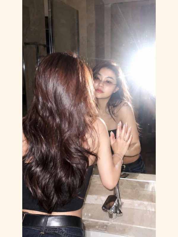 Adult red-haired woman taking a mirror photo in a marble room